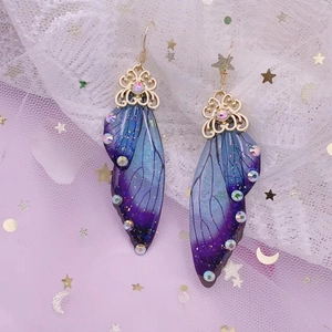 Macro shot of purple gradient butterfly wing earrings with sparkling rhinestones and gold hooks