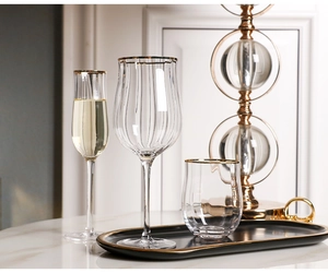 Detailed view of vertically ribbed glassware set with gold rims on a black tray