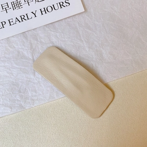 Detail of a rectangular cream PU leather hair clip with lychee texture and rounded edges