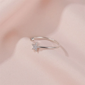 Macro detail of silver star ring with zircon inlay on pink silk fabric background