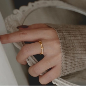 Detailed view of rose gold ring with micro-set stones and mother of pearl on a finger