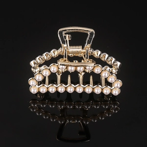 Macro detail of gold alloy hair claw clip featuring inlaid faux pearls and sleek rhinestones
