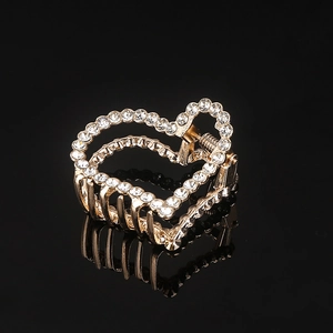 Detailed view of heart-shaped gold hair claw clip with sparkling white rhinestones