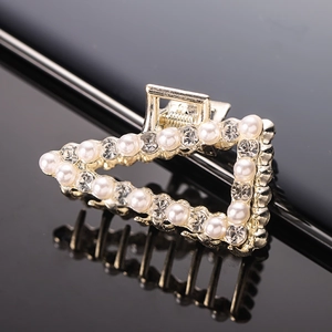 Detail of a gold alloy claw clip with elegant pearls and sparkling rhinestones