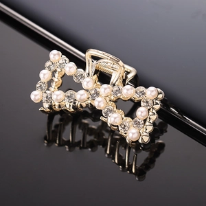 Detail of gold bow hair claw clip featuring white faux pearls and sparkling rhinestones