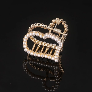 Detailed macro of gold heart hair claw clip with faux pearl embellishments and reflection