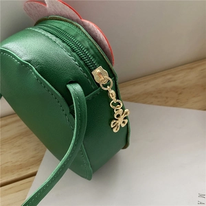 Close-up of green kids crossbody bag showing PU leather stitching and golden flower zipper