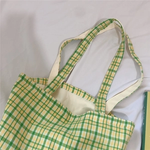 Detail of green and yellow plaid canvas tote bag showing interior lining and texture