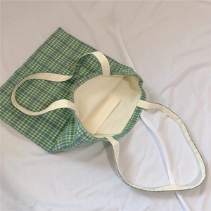Detail of green plaid canvas tote bag showing white lining and internal pocket