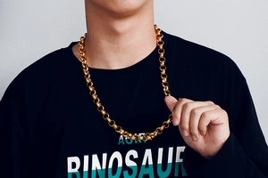 Gros plan d'un collier à maillons épais en acier inoxydable doré porté par un mannequin