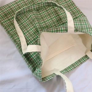 Detail view of green checkered canvas tote featuring an inner pocket and beige lining