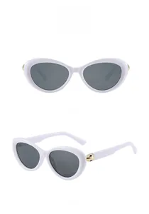 Detail of white cat eye sunglasses with gray lenses and golden textured temple decoration