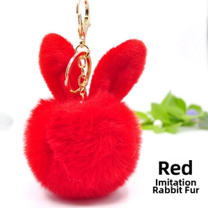Detail of red faux rabbit fur pom pom keychain with cute bunny ears and gold metal ring
