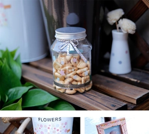 Detail of clear decorative storage jar with silver lid on rustic wooden tabletop