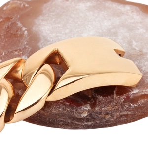 Polished thick gold titanium steel cuban chain necklace on a brown natural stone