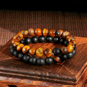 Tiger eye and matte black agate beaded bracelet set on a vintage wooden base