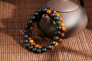 Tiger eye and matte black agate beaded bracelets draped on a brown teapot spout