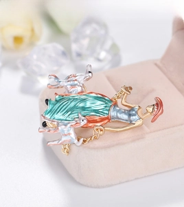 Macro shot of an elegant enamel brooch featuring a lady walking two dogs on a velvet box