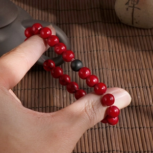 Elastic beaded couple bracelet with red turquoise and black lava stone on person's hand