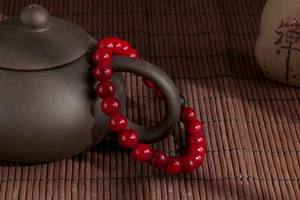 Close-up of a red turquoise beaded bracelet hanging on a traditional teapot handle