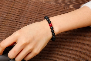 Detailed view of beaded couple bracelet with matte black agate and a red lava stone bead