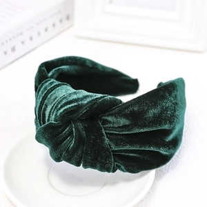 Detailed macro view of dark green velvet headband with a stylish knotted wide-brim design