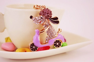 Detail of rhinestone puppy on purple scooter keychain with golden metal finish