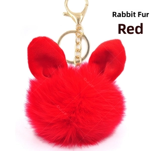 Detail of red rabbit fox fur pompom keychain with bunny ears and golden metal ring