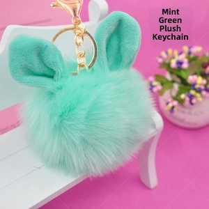 Detail view of aqua blue fur pompom keychain with bunny ears and golden metal clasp