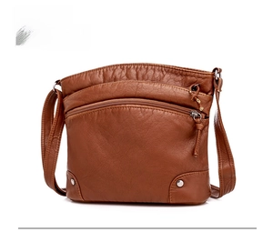 Side view of brown soft faux leather crossbody bag with zipper pocket and metal studs
