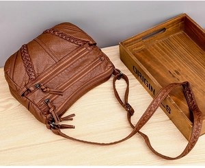 Detail showing the dark brown soft PU leather texture and multi-layer zipper pockets