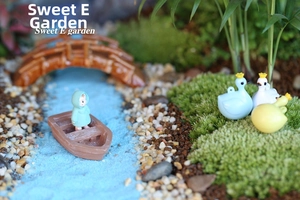 Miniature landscape set with resin boat, stone bridge and swan figurines in moss garden