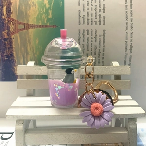 Detail of mini milk tea keychain with purple liquid, floating penguin, and daisy charm