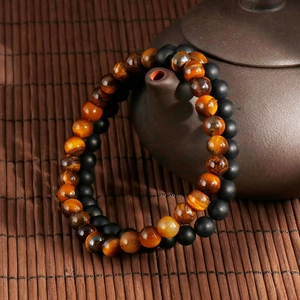 Tiger eye and matte black agate bead bracelet set displayed on a Zen teapot