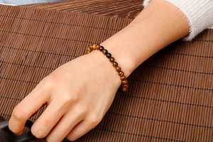 Detailed close-up of tiger eye and matte agate beaded bracelet worn on a wrist