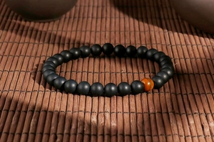 Detail of matte black agate beads and tiger eye stone on a vintage bamboo mat