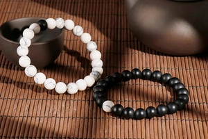 Close-up of black and white turquoise beaded bracelets on a Zen style bamboo mat