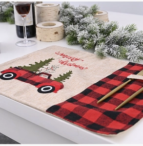 Detail of red black plaid linen placemat with Christmas truck and tree decoration
