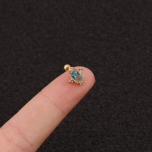 Detailed close-up of a golden cross stud earring featuring a vibrant blue oval zircon stone