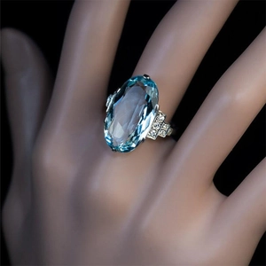 Exquisito anillo de plata con gran cristal azul ovalado y filas de diamantes brillantes
