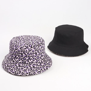 Detail of reversible leopard print and solid black canvas sun hats on white backdrop
