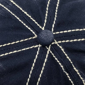 Macro detail of high-quality contrast stitching and top button on a cotton baseball cap
