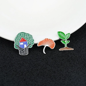 Set of three enamel pins featuring a green tree, orange ginkgo leaf, and green seedling