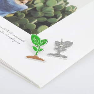 Detail showing the front and back of a plant-shaped enamel pin on a magazine background