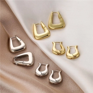 Polierte 18K Gold und Silber geometrische Creolen auf seidigem Satinhintergrund