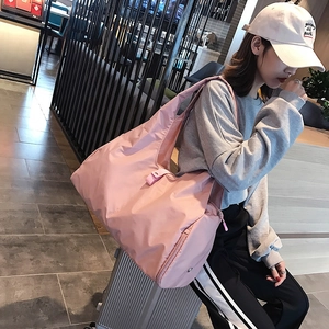 Pink large capacity foldable waterproof yoga travel bag displayed on a silver suitcase