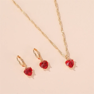 Gros plan sur l'ensemble collier et boucles d'oreilles dorés avec cristaux cœur rouges