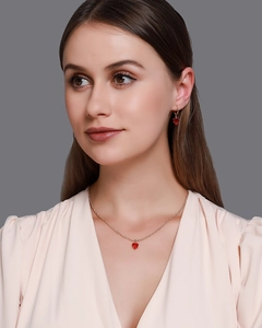 Gros plan d'un collier doré et boucles d'oreilles cœur sertis de cristaux rouges