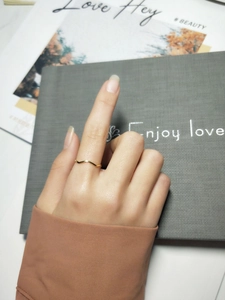 Close-up of elegant gold wave-shaped adjustable ring worn on finger with stylish background