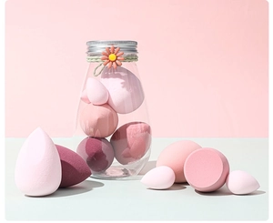 Close-up of pink makeup sponges in various shapes inside a glass jar with flower detail